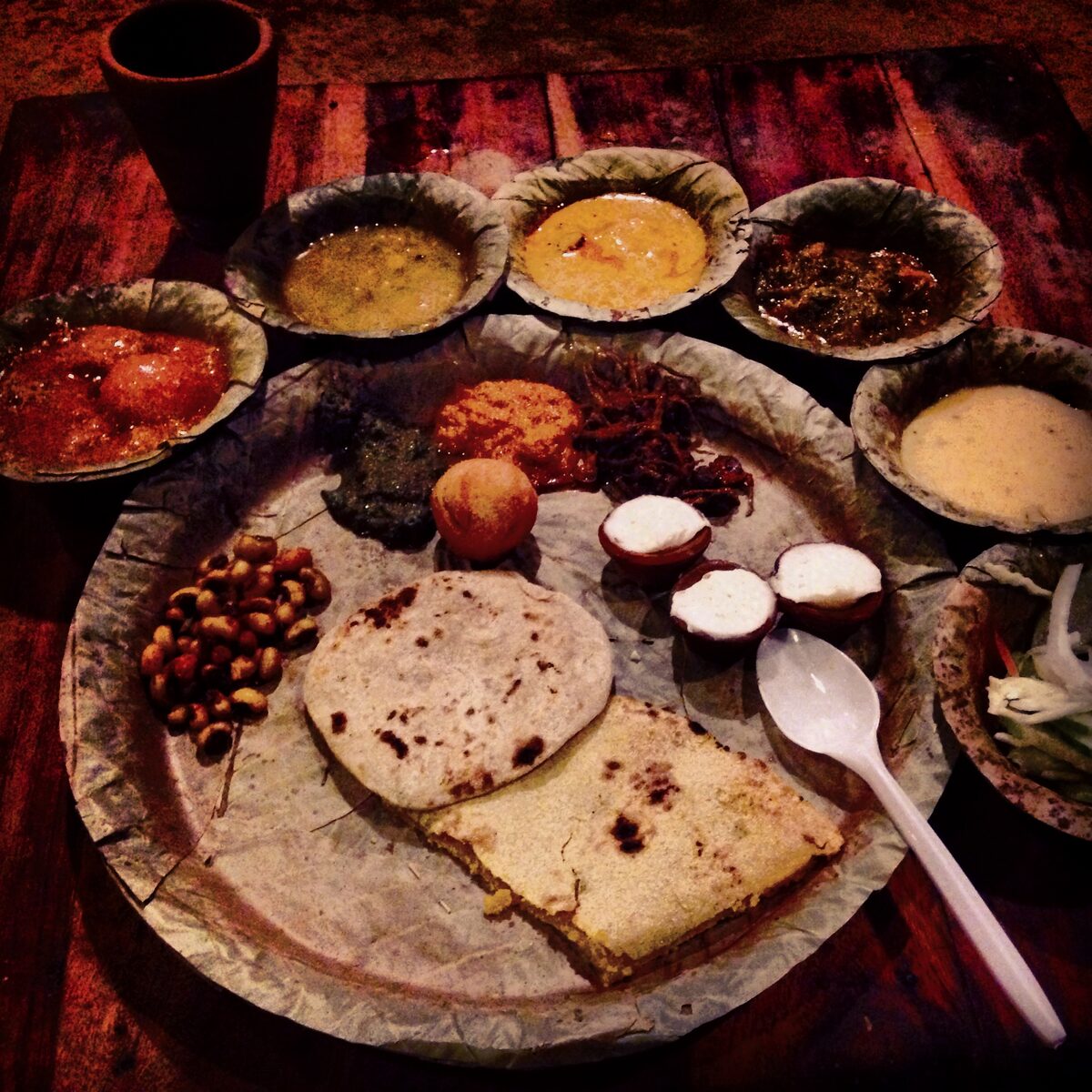 A traditional Rajasthani thali spread with an assortment of small bowls, roti and rice on a wooden table